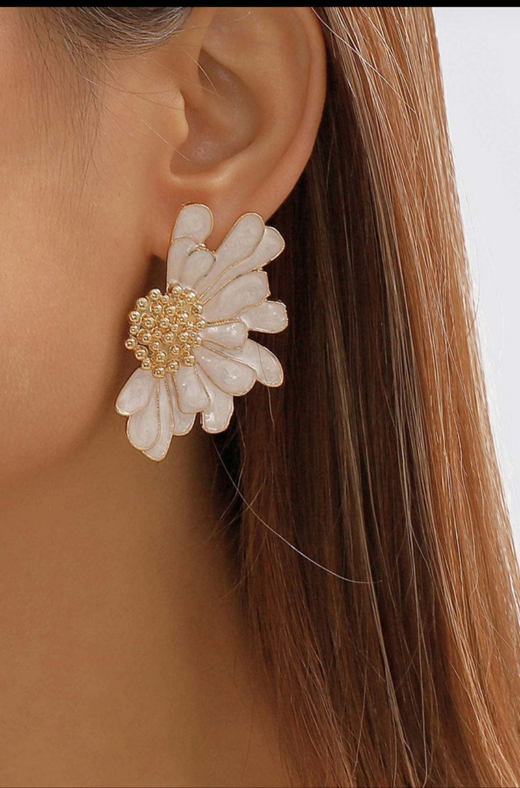 Close-up of a person wearing a floral earring with gold center.